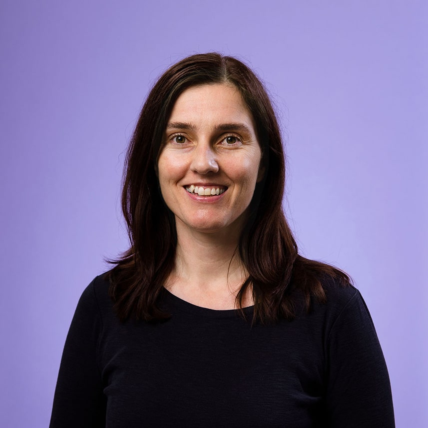 Carly Moorfield, 粉红女郎 Support Liaison, smiling at the camera against a purple background